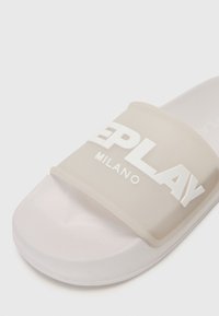 Sandale blanche à glissière avec une large sangle translucide portant "REPLAY MILANO" en lettres blanches en relief.