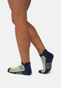 Calze atletiche navy e grigie con un design a rete, dettagli in verde neon e bordo a costine. Materiale leggero per traspirabilità e supporto.