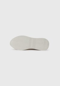 Semelle de chaussure avec un motif de bande de zigzag en beige clair, arborant le nom de la marque "Tommy Hilfiger" embossé au centre.