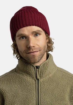 Red ribbed beanie made of knitted fabric, featuring a textured design. Paired with a light olive fleece jacket with a zippered collar.