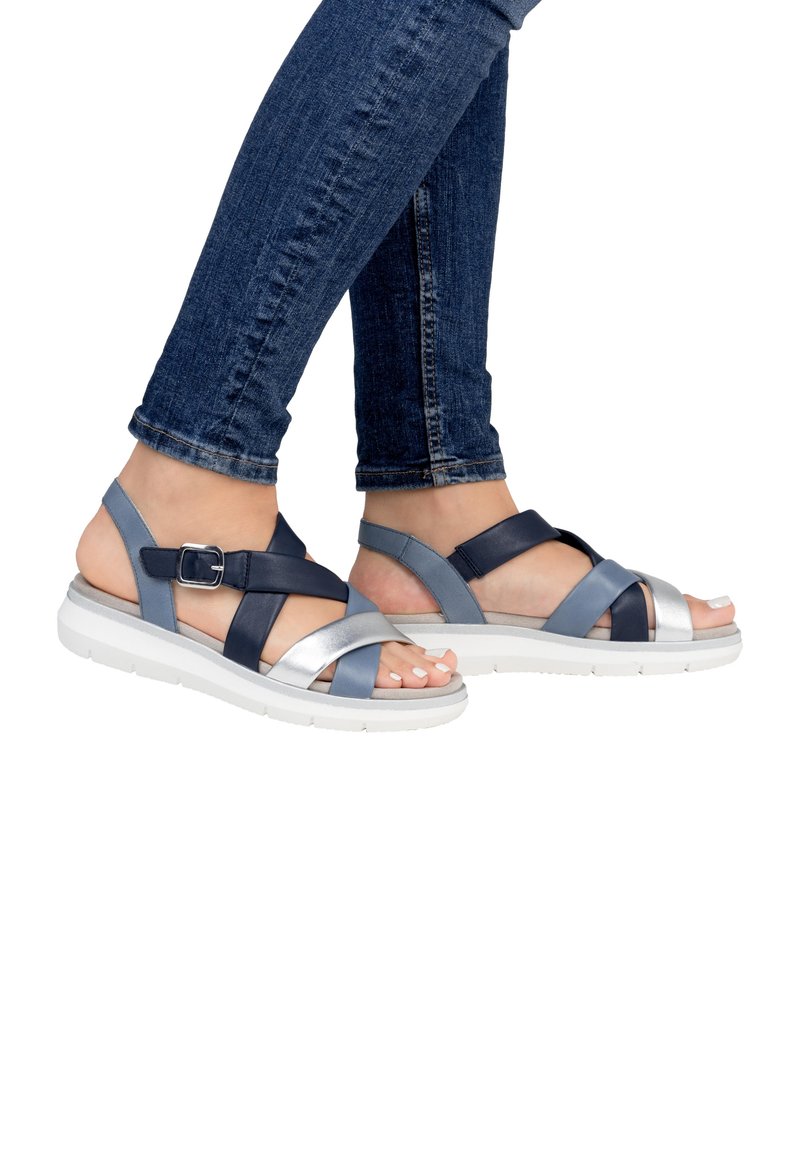 Riemchensandalen aus einer Mischung aus Marineblau, Hellblau und silbernen Materialien. Mit verstellbarem Schnallenverschluss, weißer Sohle und lässigem Design.