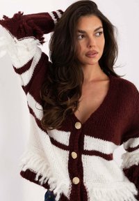 Bordowo-biały sweter na guziki z frędzlami na krawędziach, z dekoltem w serek, złotymi guzikami oraz poziomym wzorem pasków na rękawach.