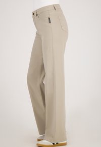 Beige wijde broek van een katoenmix, met een ritsluiting, achterzakken en subtiele stikseldetails. Geschikt voor casual of semi-formele gelegenheid.