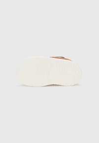 White sneaker sole with textured rubber tread. Black and orange accents visible on the upper section, featuring a smooth finish.