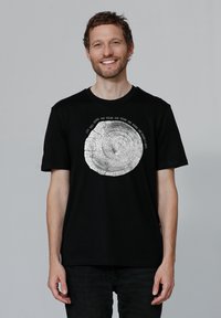 Schwarzes Baumwoll-T-Shirt mit einem kreisförmigen Baumring-Graphic in Weiß, umgeben von Text. Kurze Ärmel und Rundhalsausschnitt.
