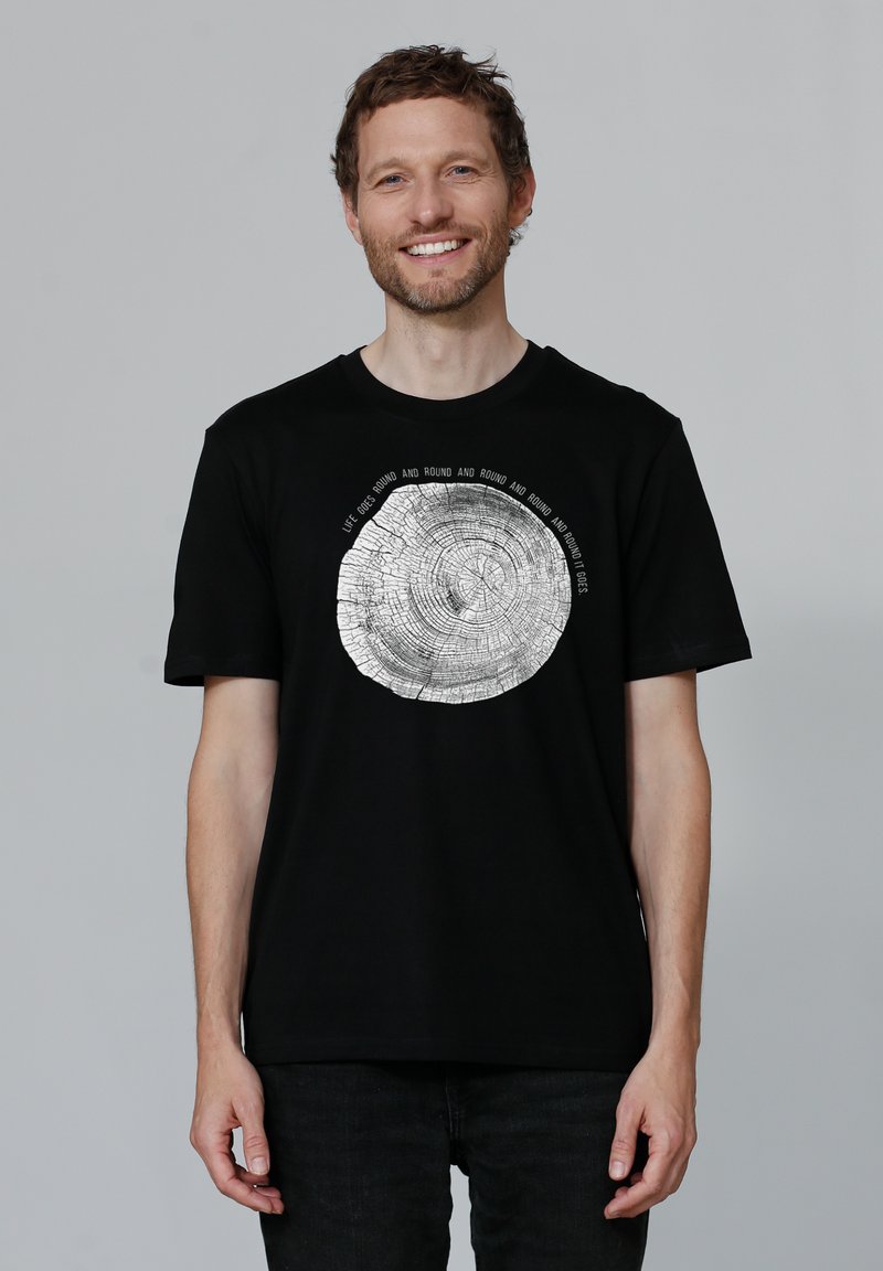 Schwarzes Baumwoll-T-Shirt mit einem kreisförmigen Baumring-Graphic in Weiß, umgeben von Text. Kurze Ärmel und Rundhalsausschnitt.