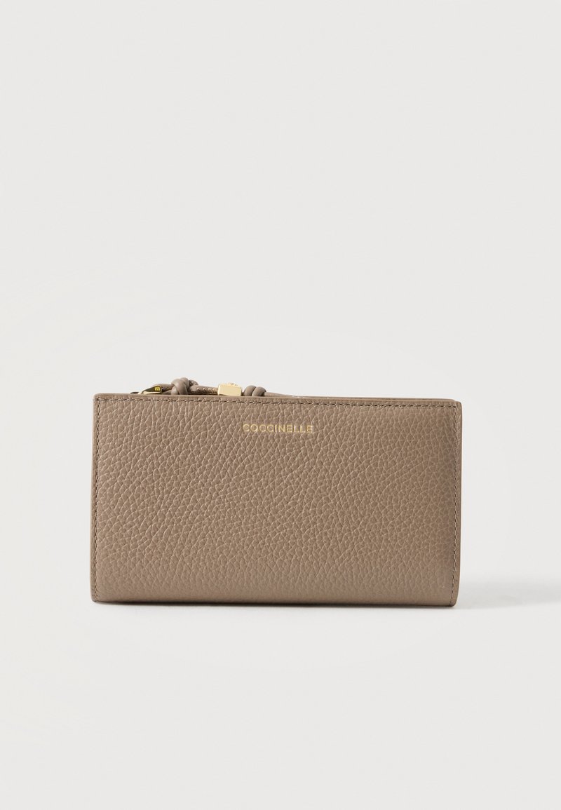 Portefeuille en cuir texturé taupe avec fermeture éclair dorée et petit nom de marque doré « COCCINELLE » au centre devant.
