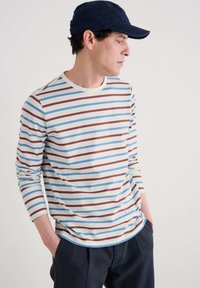 T-shirt a maniche lunghe a righe con strisce orizzontali blu, rosse e bianche su uno sfondo beige chiaro. Design con collo a giro, tessuto morbido.