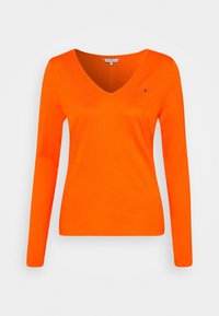Langærmet V-hals t-shirt i lys orange, lavet af blødt stof; har et lille logo-accent på venstre brystområde.