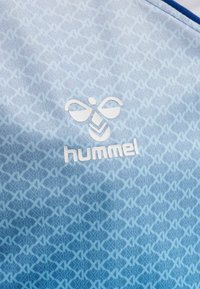 Lysblåt sportsstof med et geometrisk mønster, med et hvidt "hummel" logo og en subtil tekstur for ekstra detalje.