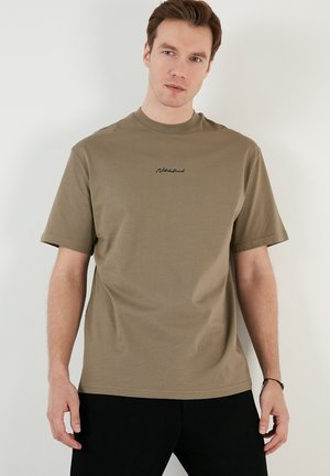 Olivengrøn kortærmet T-shirt i blødt bomuldsstof, med rund halsudskæring og subtilt sort broderet logo på brystet.