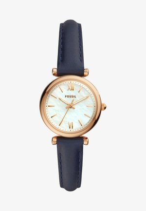 Montre Fossil dorée avec un cadran en nacre blanche, chiffres romains et un bracelet en cuir bleu. Boîtier rond et design minimaliste.