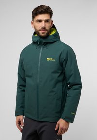 Veste imperméable turquoise avec un logo jaune, capuche ajustable et poignets en velcro. Texture lisse, fermeture éclair avant et poches latérales.