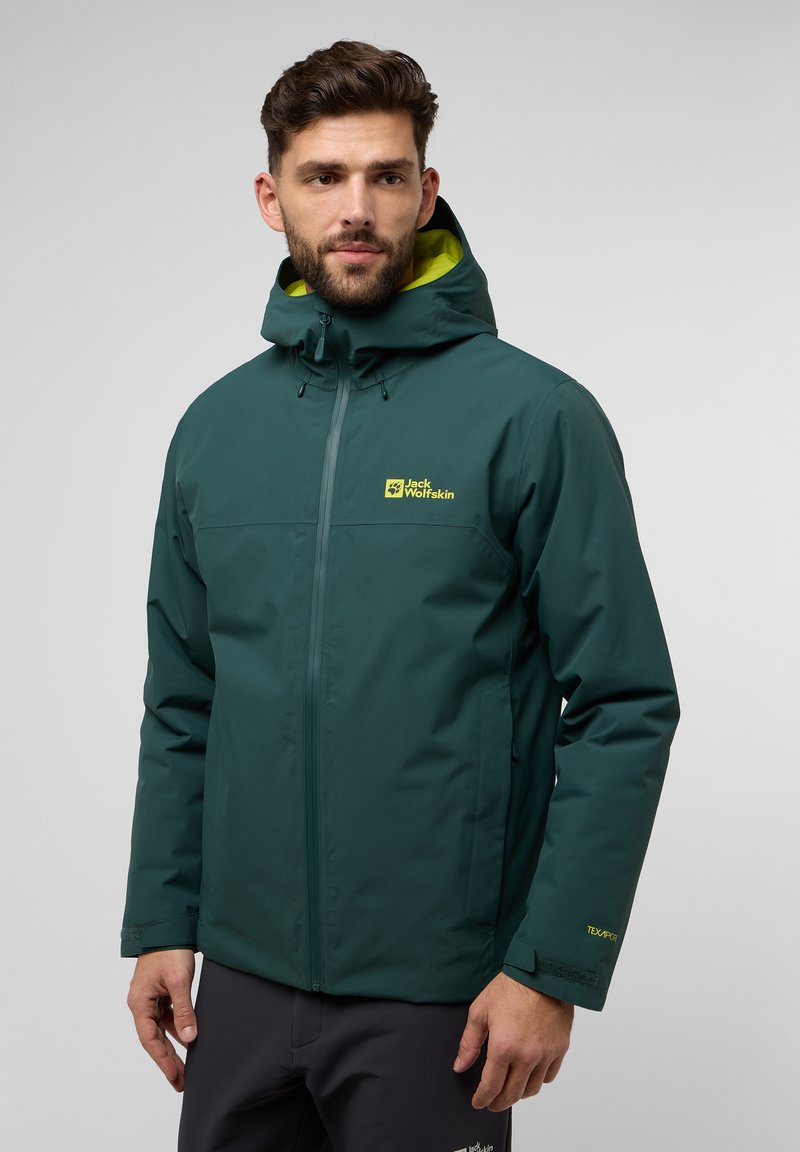 Veste imperméable turquoise avec un logo jaune, capuche ajustable et poignets en velcro. Texture lisse, fermeture éclair avant et poches latérales.