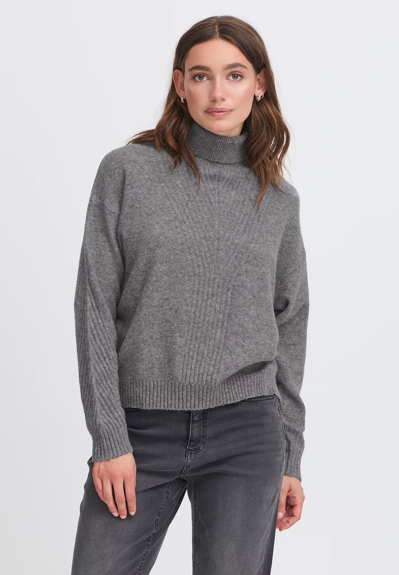 Maglione grigio lavorato a maglia con collo alto, caratterizzato da una texture a coste ai polsini e all'orlo, e una vestibilità comoda. Indossato con jeans grigio scuro.