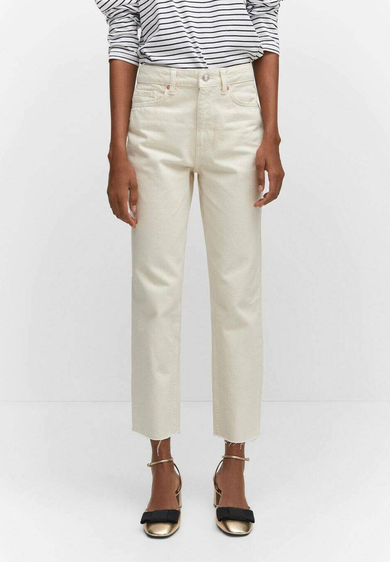 Cremefarbene gerade Jeans mit hohem Bund und rohem Saum. Kombiniert mit einem schwarz-weiß gestreiften Langarmoberteil und goldenen Absatzschuhen.