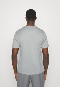 Camiseta gris de manga corta fabricada en tejido suave. Ajuste estándar con escote redondeado y sin logos ni embellishments visibles.