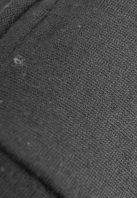 Tissu noir avec un tissage fin et texturé. La surface présente de légères fibres et une finition douce et mate, mettant en valeur l'élasticité du matériau.