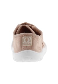 Ljusrosa canvas slip-on skor med en vit gummisula och en texturerad häl. Har ett logotagsömningar på baksidan.