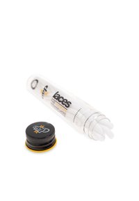 Tubo di plastica trasparente contenente lacci bianchi per sneakers con un tappo nero e giallo. Il testo sul tubo recita "I LACCI PER SNEAKERS ULTIMI".