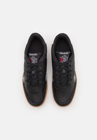 Svarta lädersneakers med en texturerad yta, vita accenter och en gummisula. Har snörning och en logotyp på tungan med en stjärndesign.