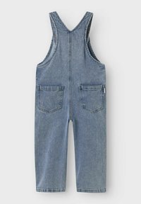 Denim kombinezoni v svetlo modri barvi z nastavljivimi naramnicami, dvema sprednjima žepoma in dvema zadnjima žepoma. Ravne hlačnice in izbledela tekstura.