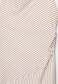 Weißer Stoff mit diagonalen kastanienbraunen Streifen, der eine glatte Textur und ein drapiertes Design aufweist, das einen fließenden, asymmetrischen Schnitt präsentiert.