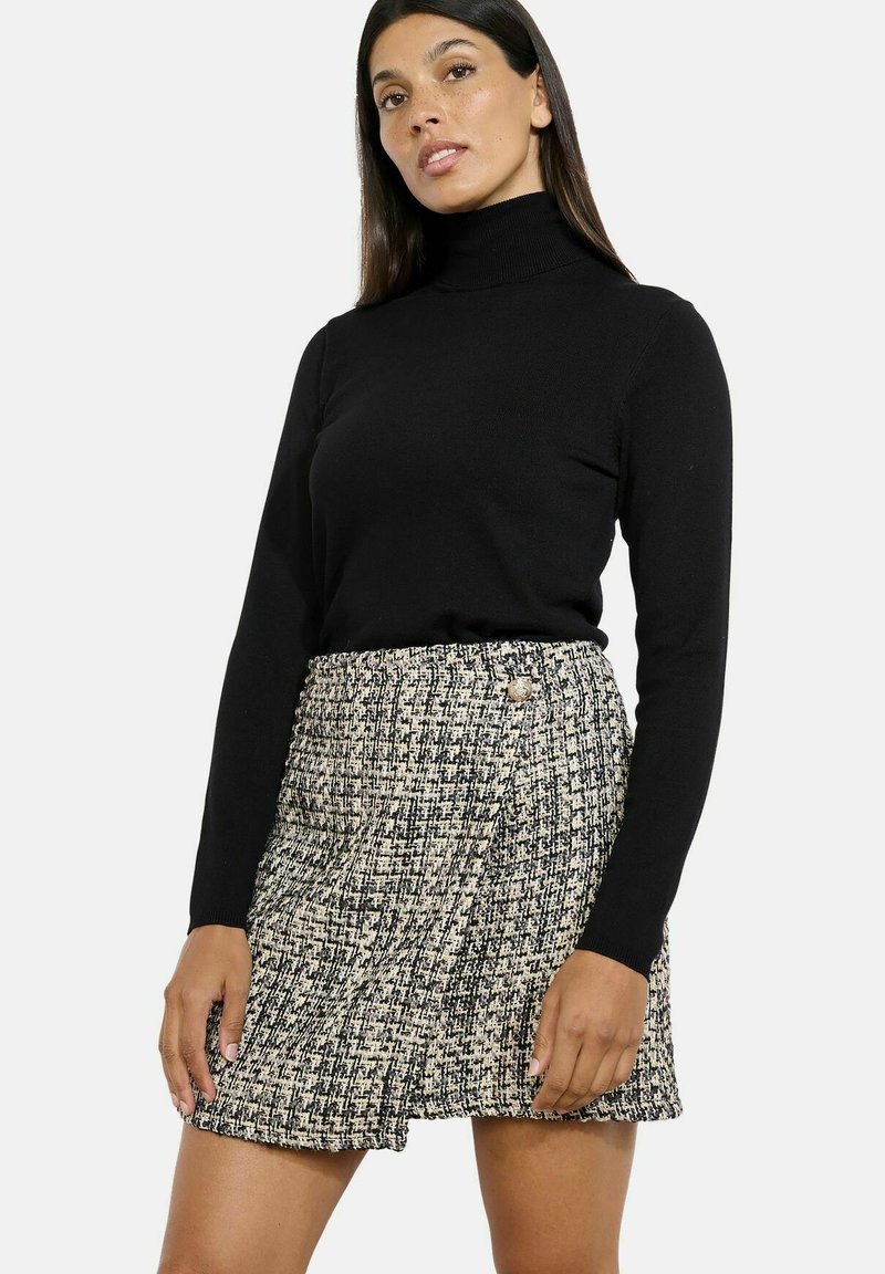 Čierny rolák v kombinácii s patterned tweed sukňou s vysokým pásom a detailmi na gombíky, v odtieňoch čiernej a bielej.