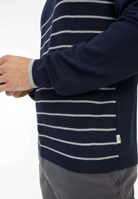 Marine gestreifter Pullover mit hellgrauen horizontalen Streifen, gerippten Bündchen und einem kleinen Logostick auf der Seite. Weiche Stricktextur.
