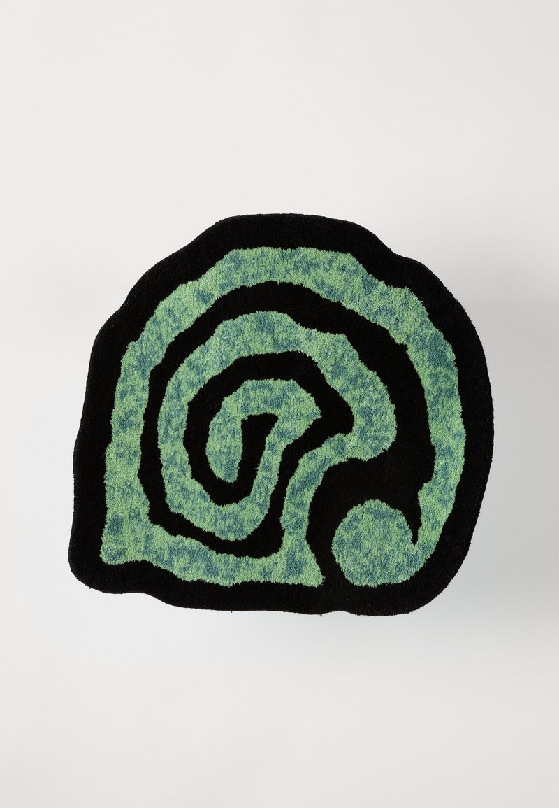 Rektangulär matta i svart med ett spiralformigt mönster i texturerade gröna nyanser. Mjuk lugg, med kontrasterande släta kanter och livfull färgvariation.