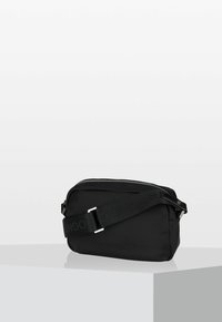 Borsa a spalla nera in nylon con forma rettangolare, chiusura con zip e tracolla regolabile, caratterizzata da un logo, superficie liscia e design minimale.