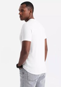 Hvid kortærmet t-shirt lavet af bomuld, med en klassisk crew neck og en normal pasform, parret med grå jeans. Glat tekstur.