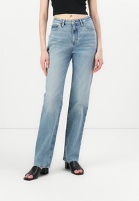 Jeans azzurri chiari a vita alta con design a gamba dritta, realizzati in denim con unaTexture liscia. Presentano una vita cucita e cinque tasche.