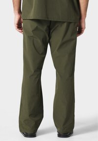 Pantalones verdes oliva de corte holgado, confeccionados en una tela ligera. Presentan una textura suave y un diseño de pierna recta. Sin herrajes visibles.