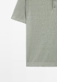 Polo shirt verde a maniche corte realizzato in tessuto morbido e texturizzato. Presenta un colletto con tre bottoni e un orlo dritto.