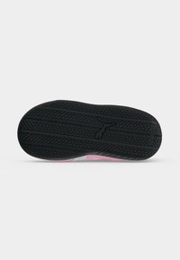 Semelle en caoutchouc noire d'une chaussure avec motif antidérapant texturé et logo Puma au centre sur un fond clair uni.
