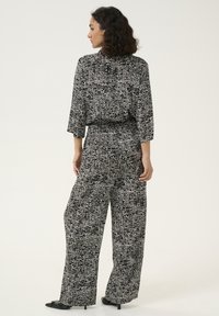 Conjunto de patrón en blanco y negro que incluye una blusa holgada y pantalones de pierna ancha. Tela suave con un diseño abstracto texturizado.