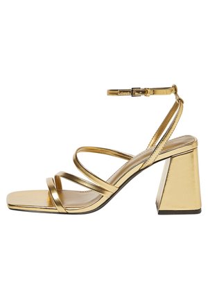 Gouden metallic open-teen sandaal met drie dunne bandjes, enkelgesp en stevige blokhak tegen een witte achtergrond.