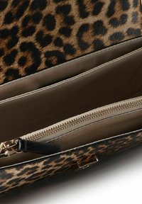 Leopardprintet clutchpung åbnet for at afsløre beige stofindvendigt med et lynlåskompartiment og sort læder lynlåstrækker.