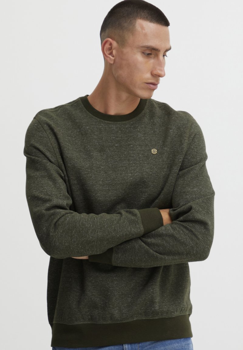 Khaki groene sweatshirt van dikke stof met een textuurafwerking, geribbelde kraag en manchetten, met een klein logo detail op de borst.