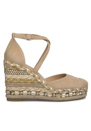 Espadrilla de cuña de ante beige con suela de yute trenzada, cuentas decorativas y acentos dorados. Cuenta con tira en el tobillo y diseño de puntera redondeada.