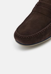 Ruske mokasine od suede s ručno šivenim detaljima, zaobljenim prstom i kontrastnom plavom i krem potplatom.
