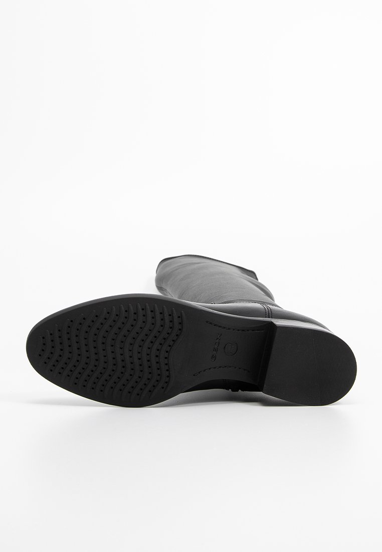 Zwarte leren kniehooglaars met een gegoten rubberen zool, voorzien van een gladde afwerking en subtiele stikdetails langs de naden.