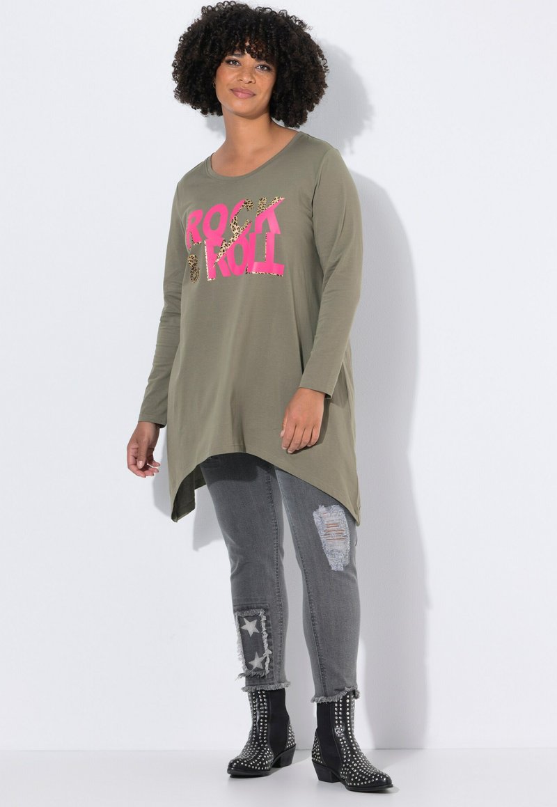 Top de manga larga color verde oliva con las palabras "ROCK" y "ROLL" en rosa y estampado de leopardo. Combinado con unos jeans grises desgastados y botas negras con tachuelas hasta el tobillo.