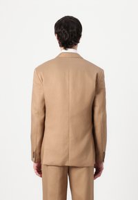 Beige suit with a tailored blazer and matching trousers. Smooth fabric with a structured design. Four buttons on each cuff.