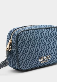 Torba na ramię z denimu w ciemnoniebieskim kolorze z tonalnym wzorem logo. Posiada złoty zamek błyskawiczny oraz skórzane akcenty wzdłuż krawędzi.