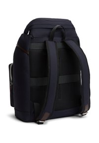 Σκούρο μπλε σακίδιο κατασκευασμένο από ανθεκτικό ύφασμα με επενδυμένη πλέκτη στην πλάτη, ρυθμιζόμενες τιράντες και τσέπη με φερμουάρ στο πλάι. Καφέ δερμάτινες λεπτομέρειες στις τιράντες.