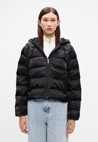 Czarna puchowa kurtka o skróconym kroju, z kapturem, zapięciem na zamek błyskawiczny i elastycznymi mankietami. Gładka, błyszcząca faktura z poziomymi przeszyciami.