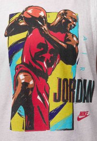 Camiseta gráfica de Nike con una ilustración multicolor de un jugador en una camiseta roja con el "23", destacándose sobre un fondo azul y amarillo.