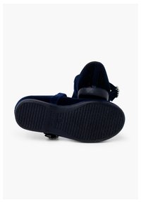 Sandalias de ante azul marino con suela plana, correa ajustable y un adorno metálico decorativo. Suela texturizada para mayor agarre.